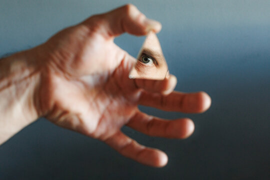 Hand Holds Triangle Mirror Shape With Eye Reflection 
