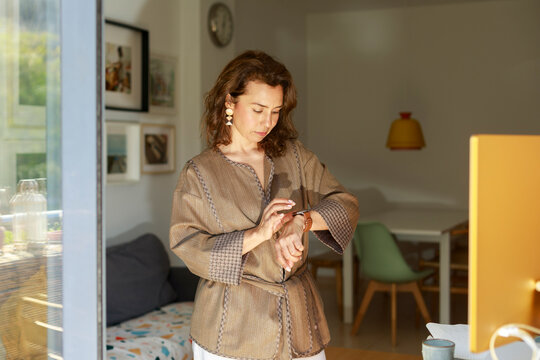 Woman Looking at Watch in a Bright Room 