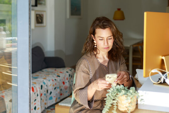 Woman Using Phone While Sitting at Desk in Cozy Workspace