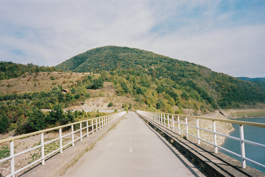 Old concrete dam bridge with river and green hill