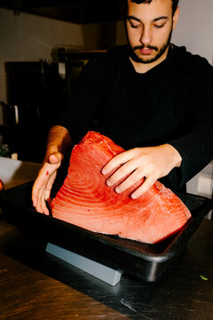 A chef measuring fresh fish on a kitchen scale