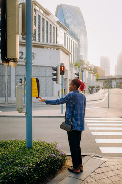 The woman presses the button to call the traffic light
