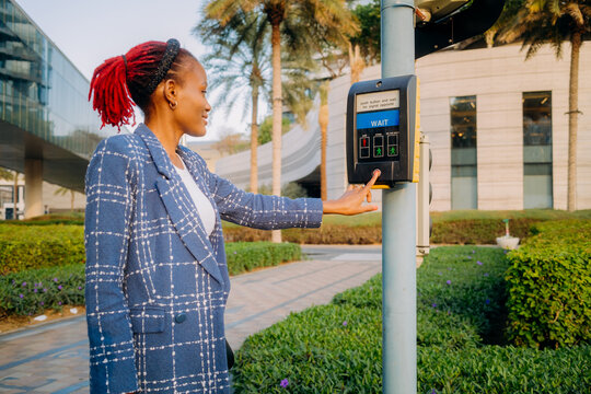 The woman presses the button to call the traffic light