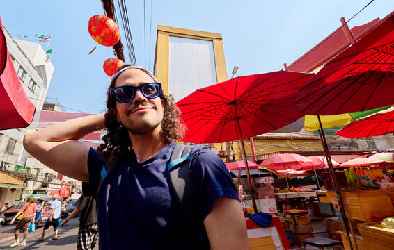 Man standing in street market with red umbrellas Bangkok Thailand