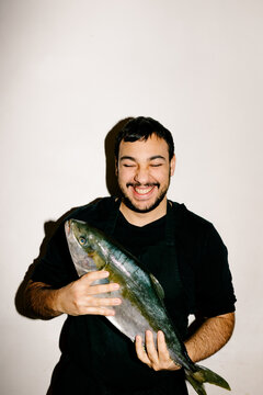 A professional chef happily presenting a freshly caught fish