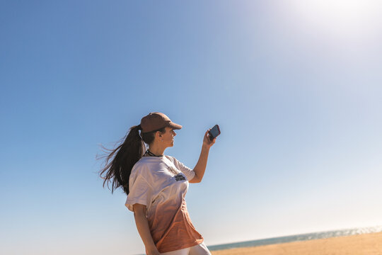 Woman using mobile phone on beach under blue sky