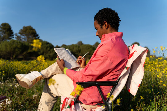 Man Writing in a Notebook While Sitting in a Field
