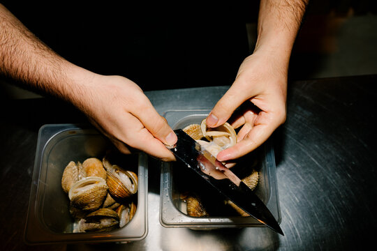 Anonymous chef shucking clams in a Canarian cuisine kitchen