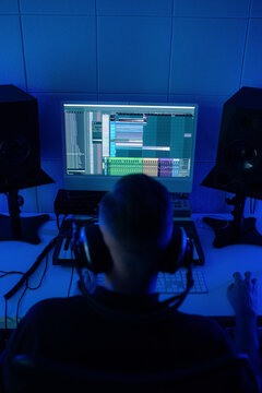 Person Works on Music Production in a Dimly Lit Studio