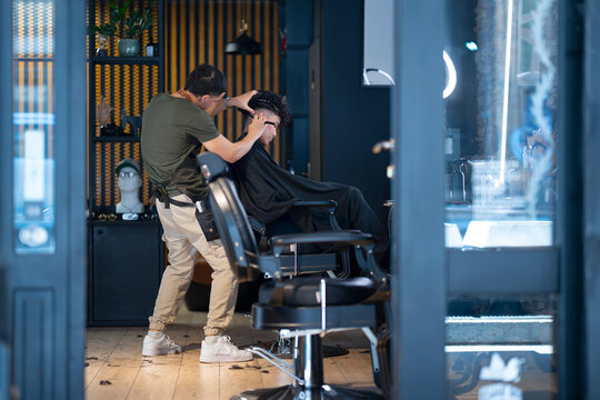 Barber cuts hair in a salon during the day