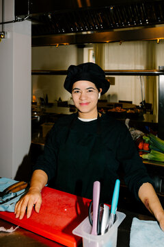 A mid-shot of a female chef, lit by a flash, smiling at the camera
