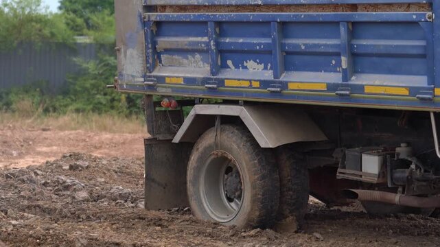 Heavy duty commercial truck tires on a dirty, muddy ground at an industrial worksite.
