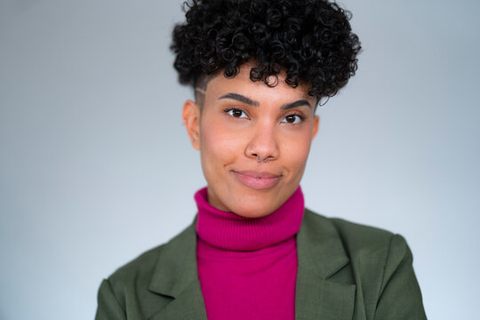 A woman stands against a simple background