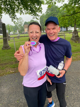 middle aged couple laughing together after finishing run holding medal