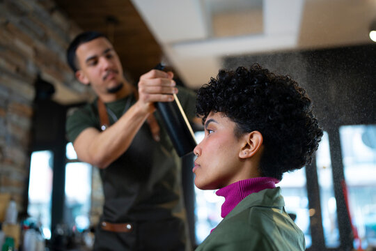 Hair stylist spritzes water on client's curls