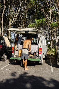 Man loading surfboard into camper van in Australia