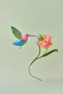 Paper hummingbird with flower on green background