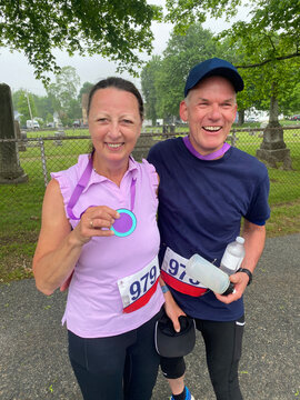 middle aged couple laughing together after finishing run holding medal