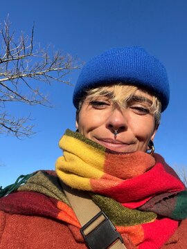 A person enjoys the sunlight while taking a selfie outdoors.