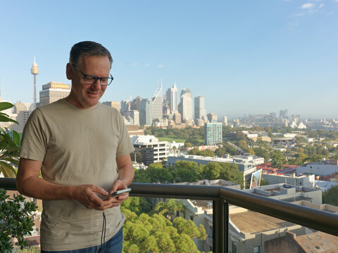 Man Looking at Phone in City With Sydney Skyline in Background