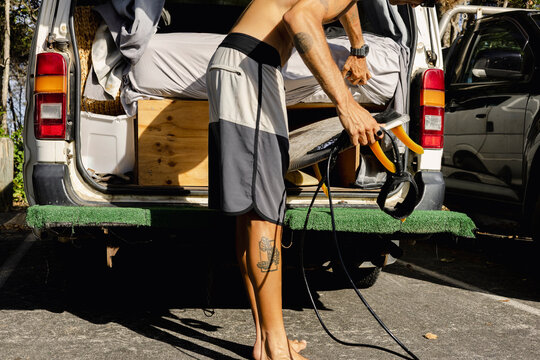 Anonymous Man handling surfboard at back of camper van in Australia
