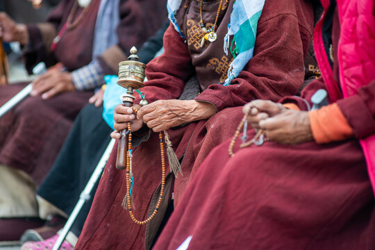Hands holding Buddhist prayer wheel and beads during ritual