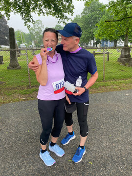 middle aged couple laughing together after finishing run holding medal
