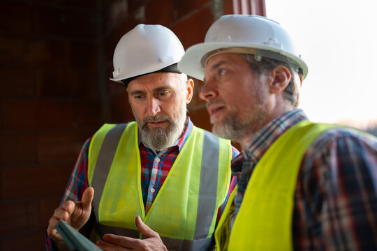 Workers discuss plans at a construction site