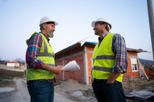 Two builders talk near a construction site