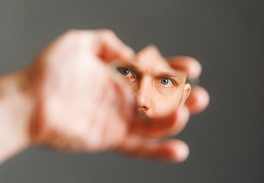 Man Looks Through Cut Shape in Hand During Creative Indoor Activity
