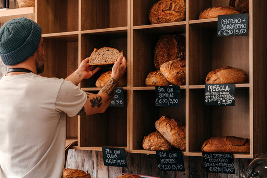 Baker Places Bread on a Shelf in a Bakery
