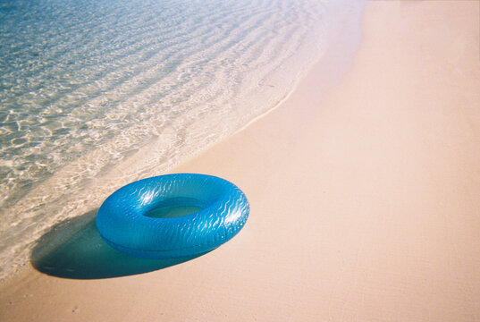 Film photo of blue inner tube on beach