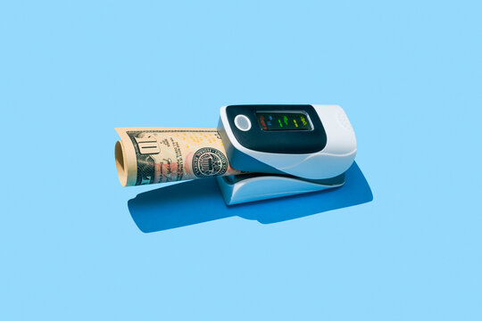 a pulse oximeter clamps a rolled US dollar bill