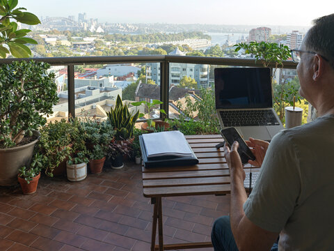 Man Works on Laptop at Balcony With Sydney City View