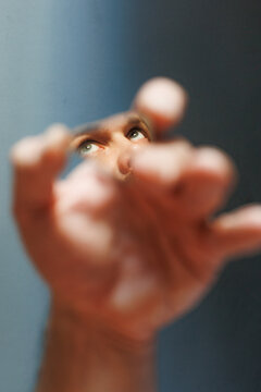 Hand Reaches Towards Mirror While Reflecting Eyes and Face
