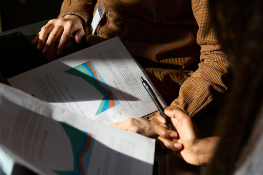 People reviewing printed charts and documents with laptop