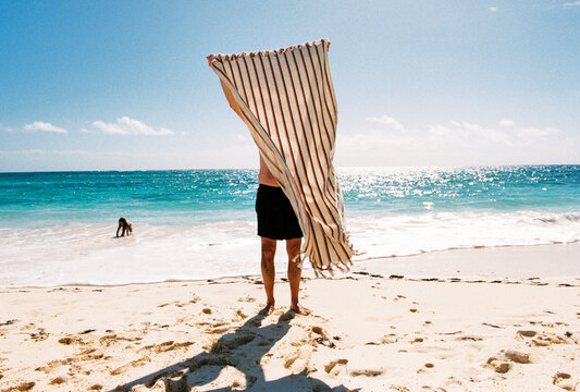 Man on vacation holds up towel on beach in Elbow Cay, Bahamas