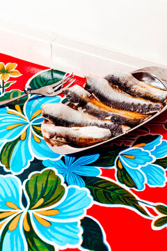 several sardines preserved in oil rest on a small metal tray