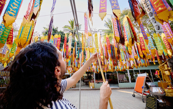 Man placing hanging decorations at temple in Thailand