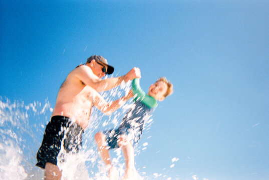 Candid family vacation action moment splashing in water on beach