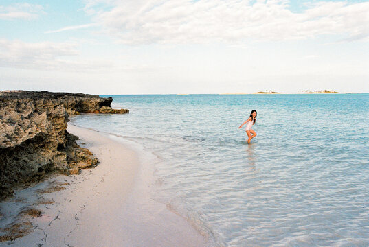 Girl on vacation in the Bahamas swimming at beach with coral rocks