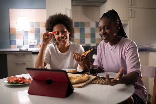 Diverse Multiracial women chatting online while sharing pizza at home