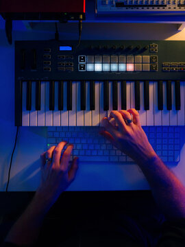Musician playing on midi keyboard while creating new song 