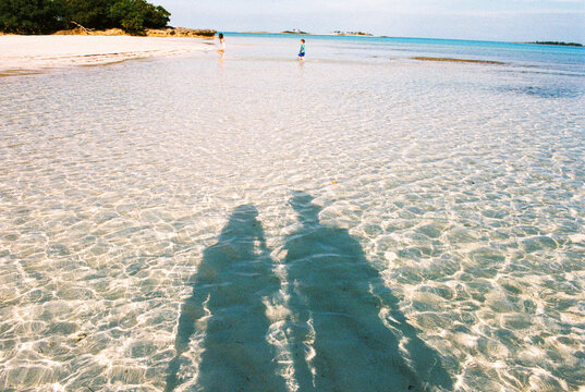 UGC family vacation shadow selfie of parents and kids on beach