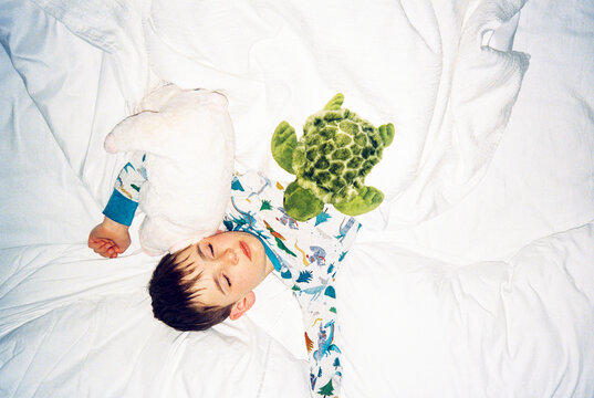 Direct flash film portrait of child sleeping in bed with stuffies