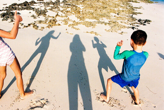 Shadows of mom with 2 kids on vacation on a Bahamas beach