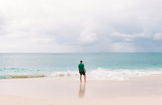 Man on vacation in the Bahamas stands on a white sandy beach