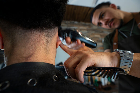 Barber cuts hair in a shop during daylight hours