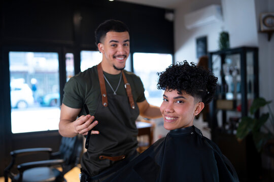 Barber cuts hair in a shop on a sunny day
