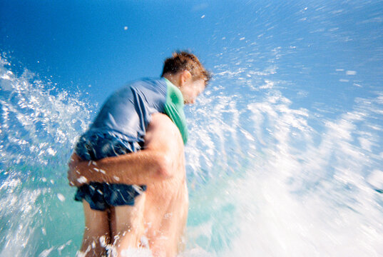 Candid action moment of father and son playing in ocean waves